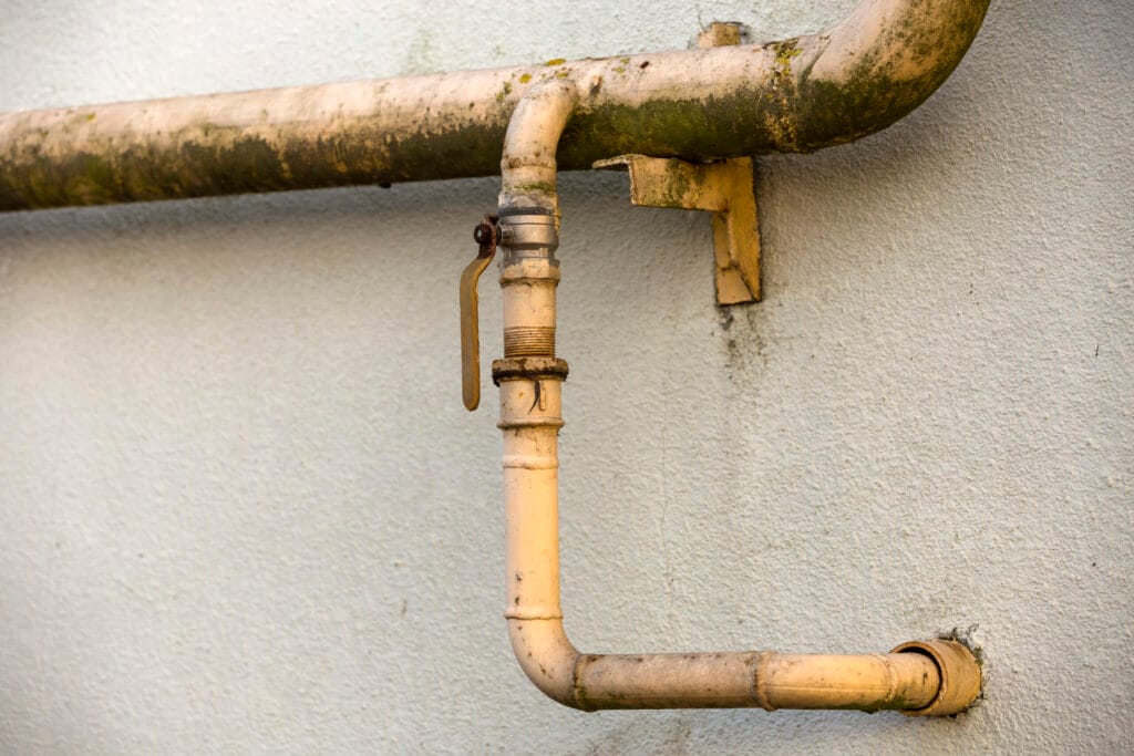 Old corroded water supply pipe on an exterior wall