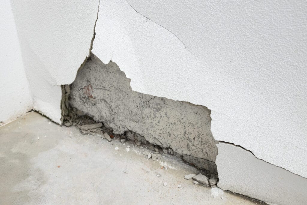 Water damage cracking plaster at the base of a wall